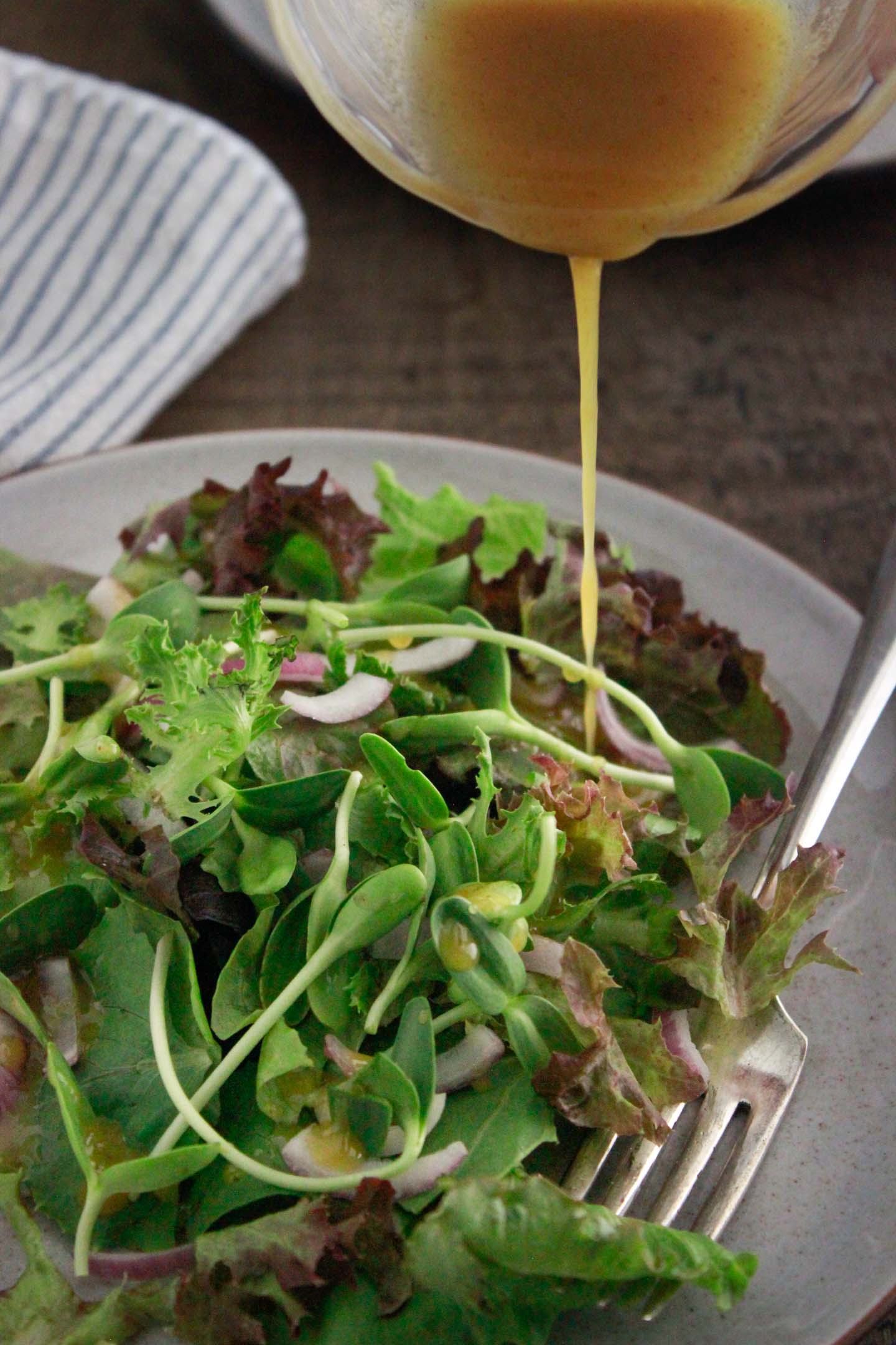 Drizzling vinaigrette over the baby lettuce salad