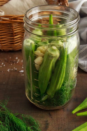Preparing okra to ferment - okra, garlic and dill are in the jar
