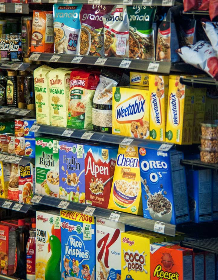 Grocery store shelves showing boxed cereals and other processed foods