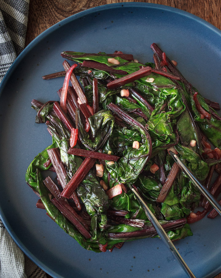 Sautéed Beet Greens being served with tongs