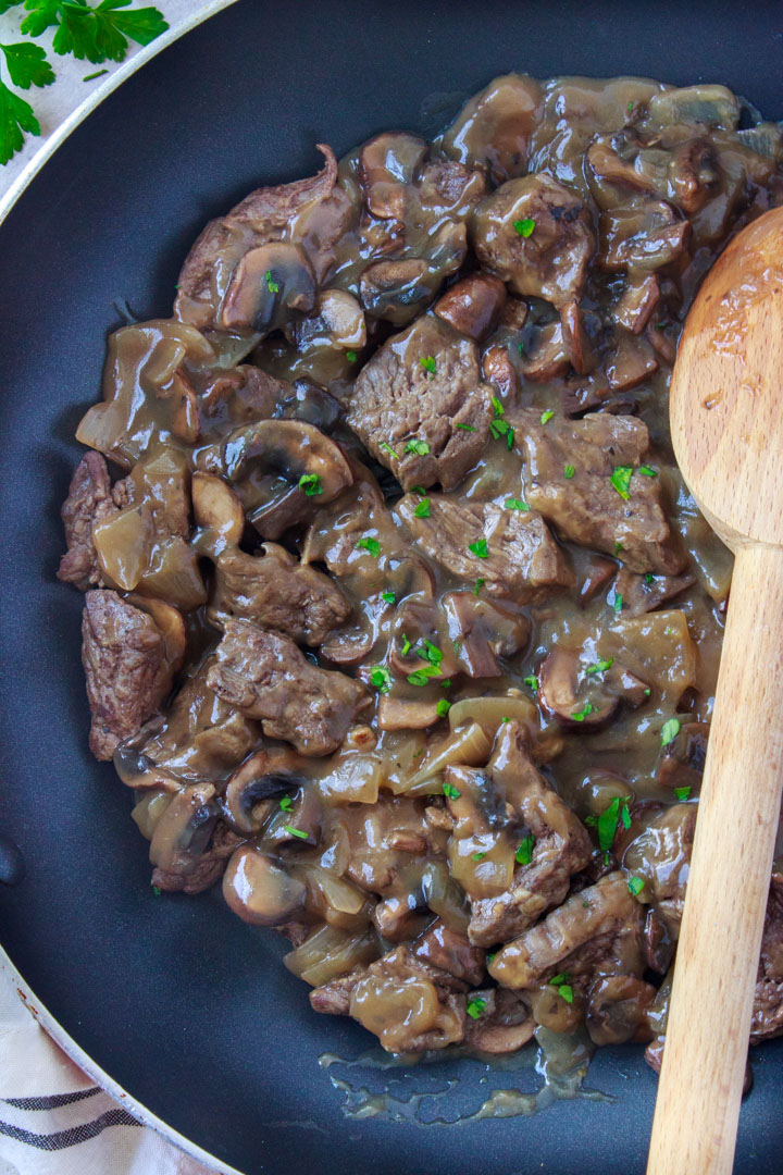 Chopped steak with mushroom and onion gravy simmering in a pan