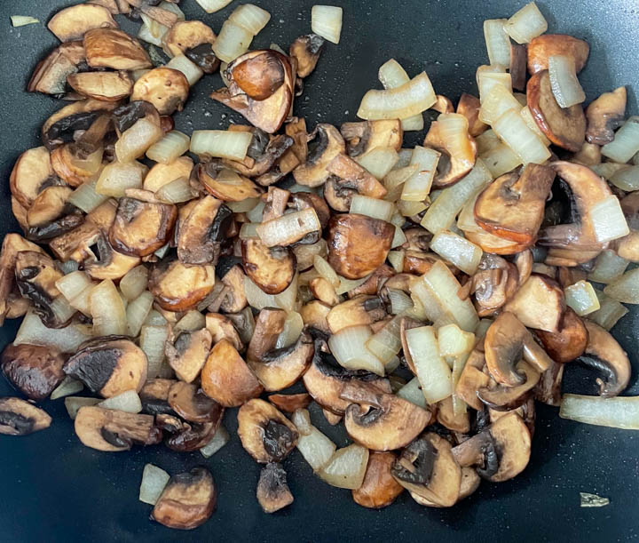 Mushrooms and onion cooking in a frying pan