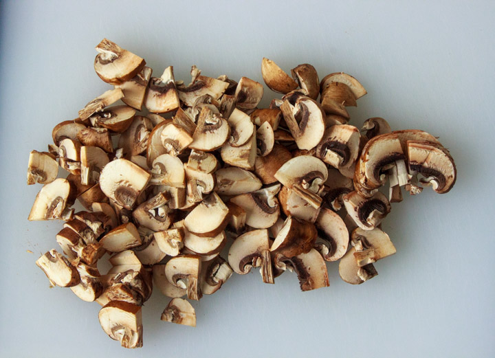 Sliced cremini mushrooms on a cutting board