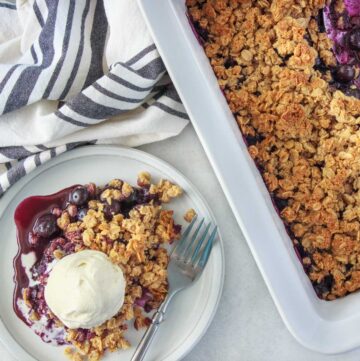 Easy Blueberry Crisp (Gluten-Free) - being served on a dessert plate with vanilla ice cream. This blueberry crisp is gluten-free because it's made with almond flour. It's sweetened with maple syrup.