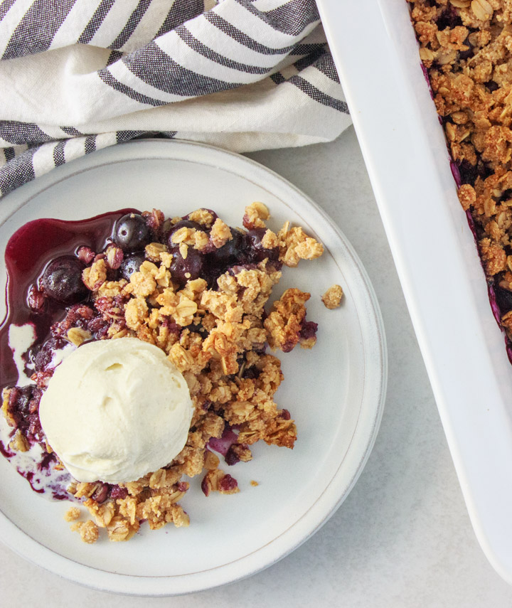 Easy Blueberry Crisp (Gluten-Free) - on a plate with a scoop of vanilla ice cream