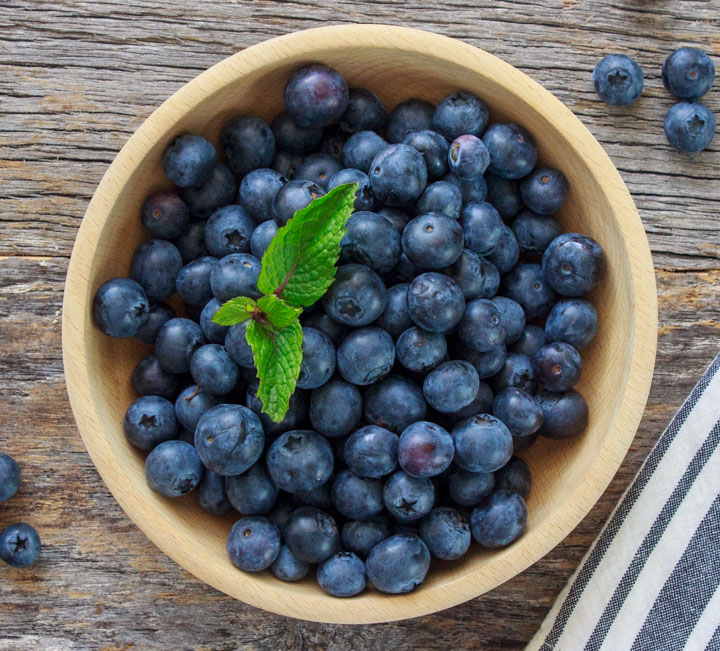 Bowl of fresh blueberries on a wooden table