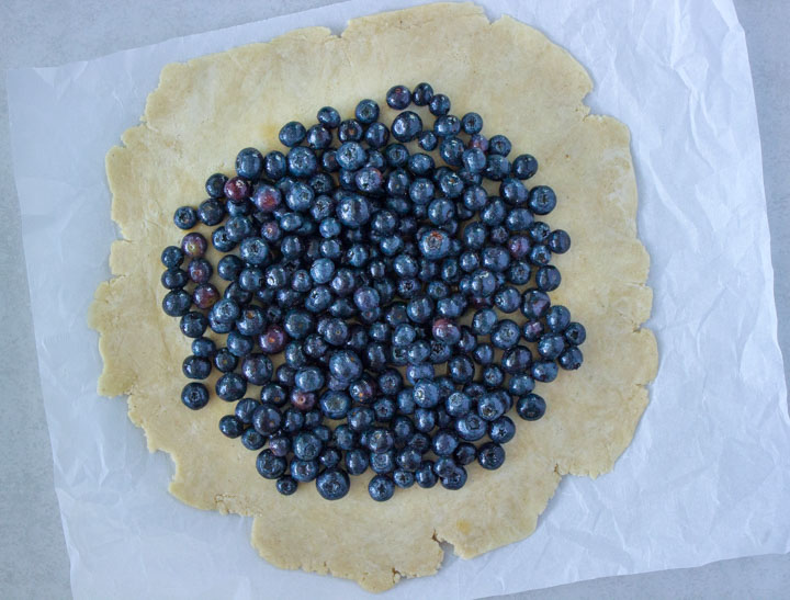 Rolled out galette dough topped with blueberries