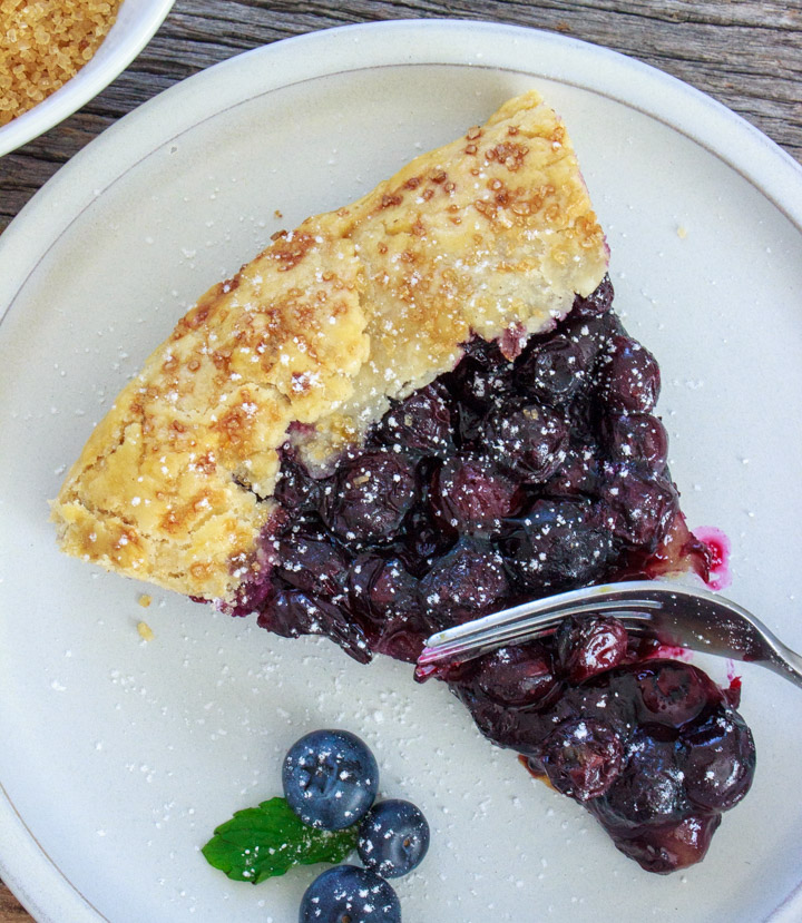 Slice of blueberry galette, cutting into it with a fork