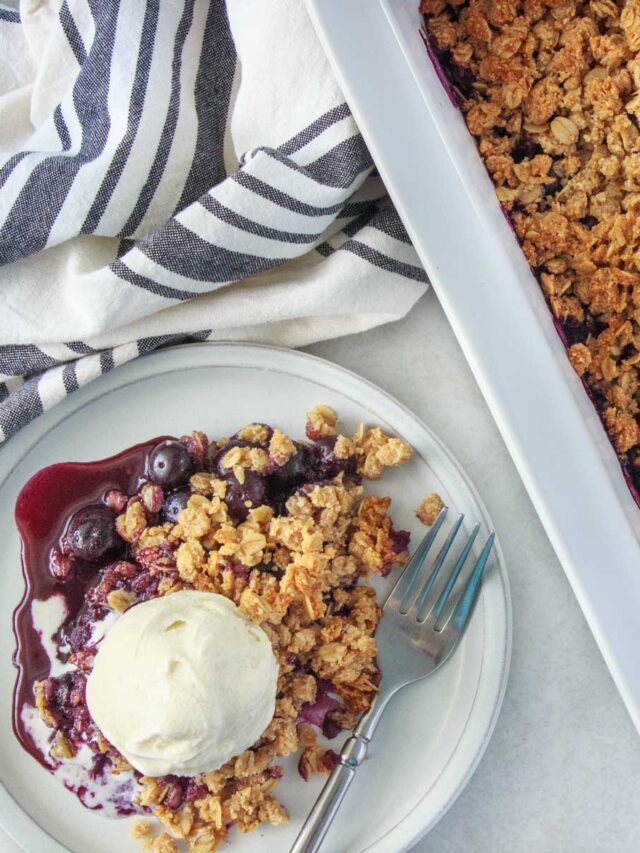 Easy Blueberry Crisp (Gluten-Free) - being served on a dessert plate with vanilla ice cream. This blueberry crisp is gluten-free because it's made with almond flour. It's sweetened with maple syrup.