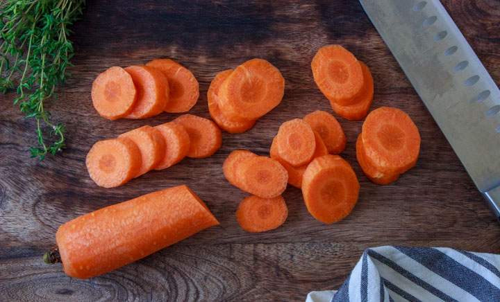 Sliced carrots on a cutting board for making maple glazed carrots