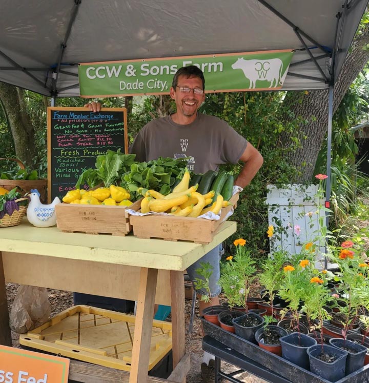 Calvin of CCW & Sons posing in front of his farmers market booth at Sweetwater Farm