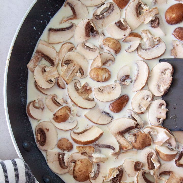 Mushrooms simmering in cream to make a mushroom cream sauce