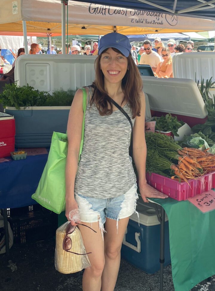 Photo of me at the farmers market with a backdrop of farm fresh produce