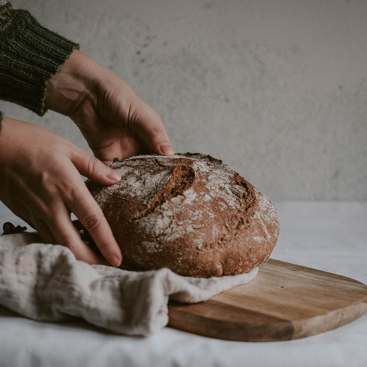 Girl placing a loaf of homemade artisan bread on a cutting board.