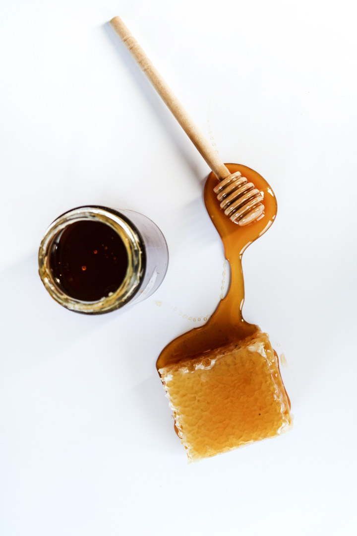 A jar of unfiltered honey and a piece of honeycomb dripping with honey