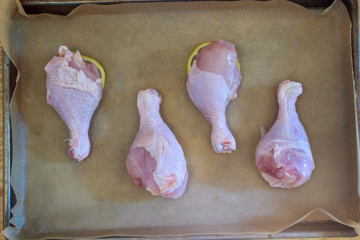 Easy One Pan Lemon Chicken Drumsticks and Potatoes - Step 2: Sheet pan with sliced lemon and chicken drumsticks