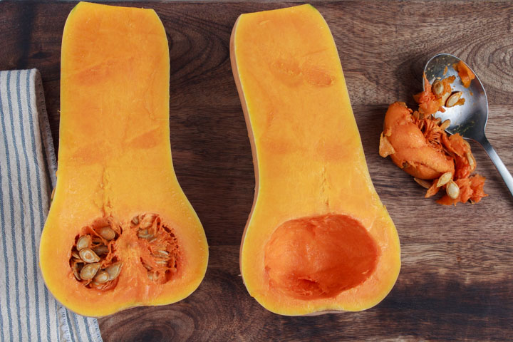 Butternut squash sliced in half and removing the seeds and pulp
